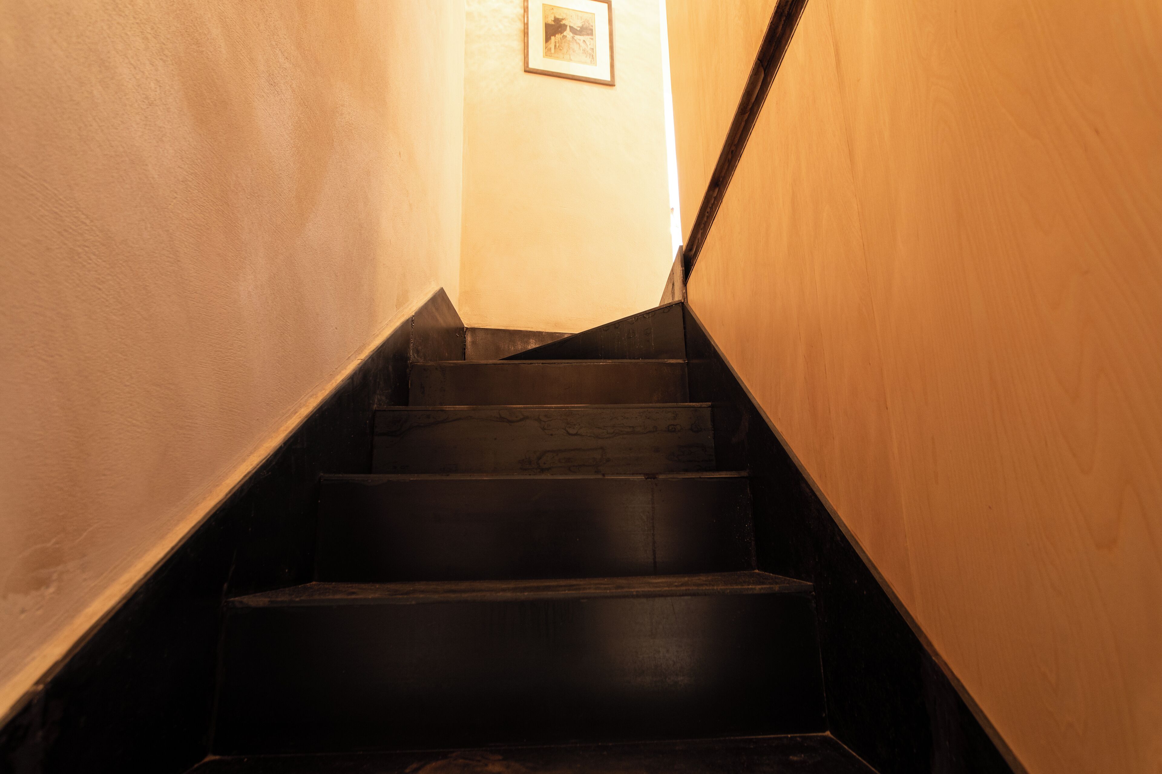 A staircase with a wooden handrail and a picture on the wall.