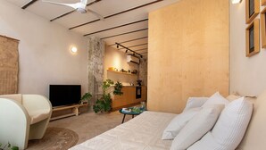 A modern bedroom with a large bed, a TV, a wooden cabinet, and a dining area. - Vintage Eclectic Loft by Sea N' Rent (Tel Aviv)
