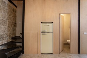 A compact kitchen with a vintage refrigerator, wooden cabinets, and a stone wall. - Vintage Eclectic Loft by Sea N' Rent (Tel Aviv)