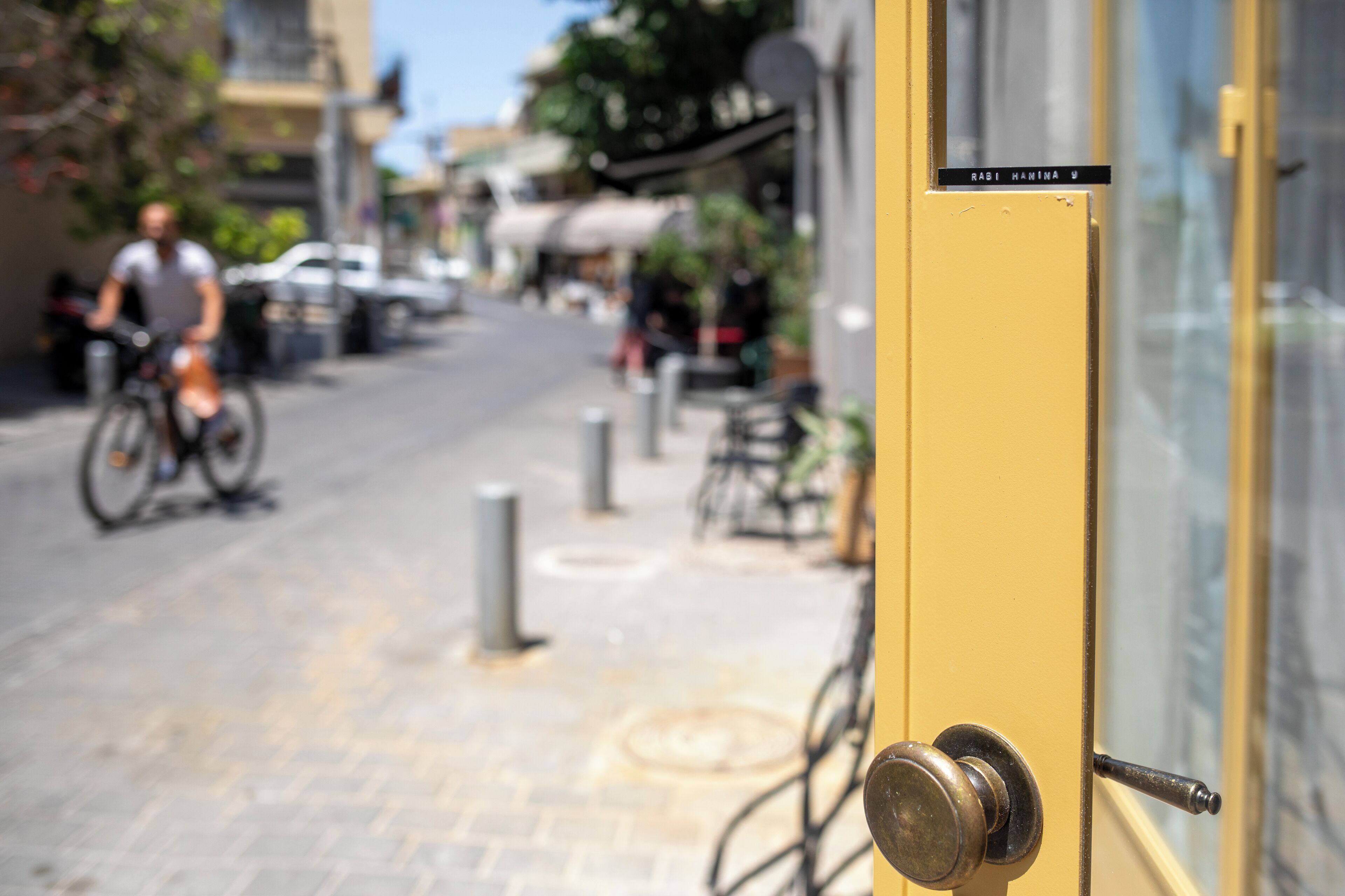 A yellow door with a sign reading "RABI HAMINA U" and a metal handle.