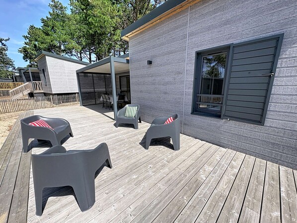 A deck with outdoor seating and a modern building with a large window.