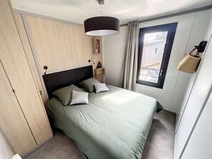 Quarto com cama, guarda-roupa, janela com cortinas e cesto suspenso.
