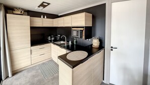 Eine moderne Küche mit hellen Holzschränken, einer schwarzen Arbeitsplatte und einer eingebauten Mikrowelle.
