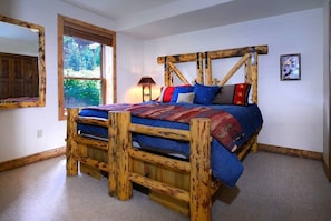 Una cama de madera rústica con cabecera, una ventana con persianas, una lámpara y un cuadro en la pared.