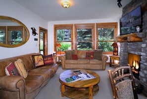 Ein gemütliches Wohnzimmer mit Ledersofas, einem Couchtisch und einem Kamin.