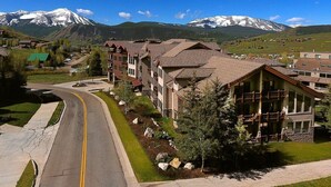 A residential area with a curved road, houses with balconies, and a mountain range in the background.