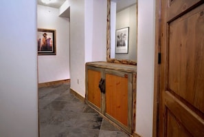A hallway with a wooden cabinet and a mirror.