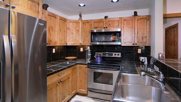 A kitchen with wooden cabinets, stainless steel appliances, and a granite countertop.
