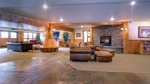 A spacious lobby with a stone fireplace, leather sofas, and a large wooden table.