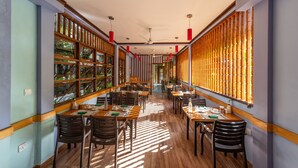 Un restaurante con piso de madera, mesas, sillas y separadores de bambú.