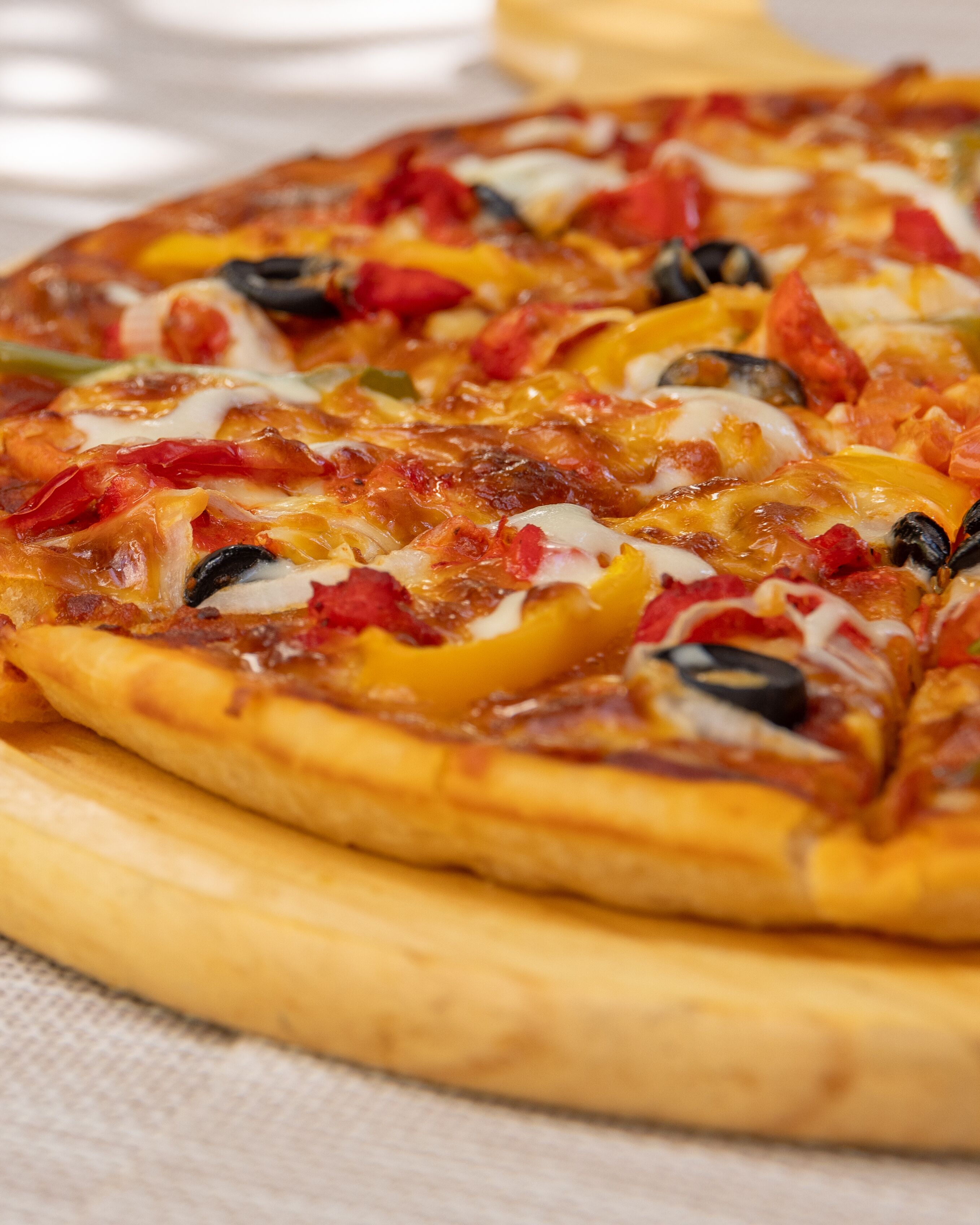 A pizza with various toppings on a round wooden board.