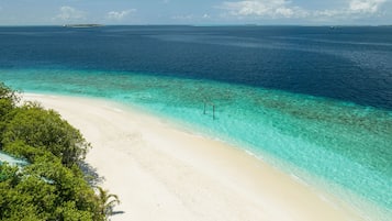 Una playa cerca, arena blanca, sillas reclinables de playa