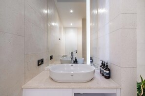 A modern bathroom with a large oval sink, a mirror, and a toilet. - Green Flow Villa 8 (Ubud)