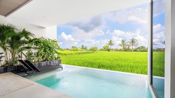 A modern indoor pool with a view of a green field and a clear sky.