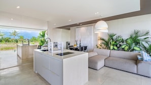 A modern kitchen with a central island, a dining area with a sofa, and a view of the outdoors.
