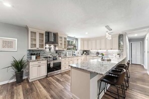 A modern kitchen with white cabinets, a granite countertop, and a central island with bar stools.
