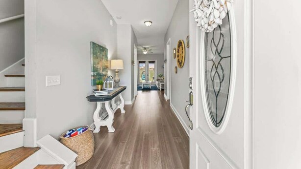 A hallway with a staircase, a table with a lamp, and a decorative wall piece. - Coconut Cove (Jacksonville Beach)