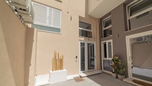 Edifici modern amb façana beix, grans portes corredisses de vidre i zona de pati amb paviment.