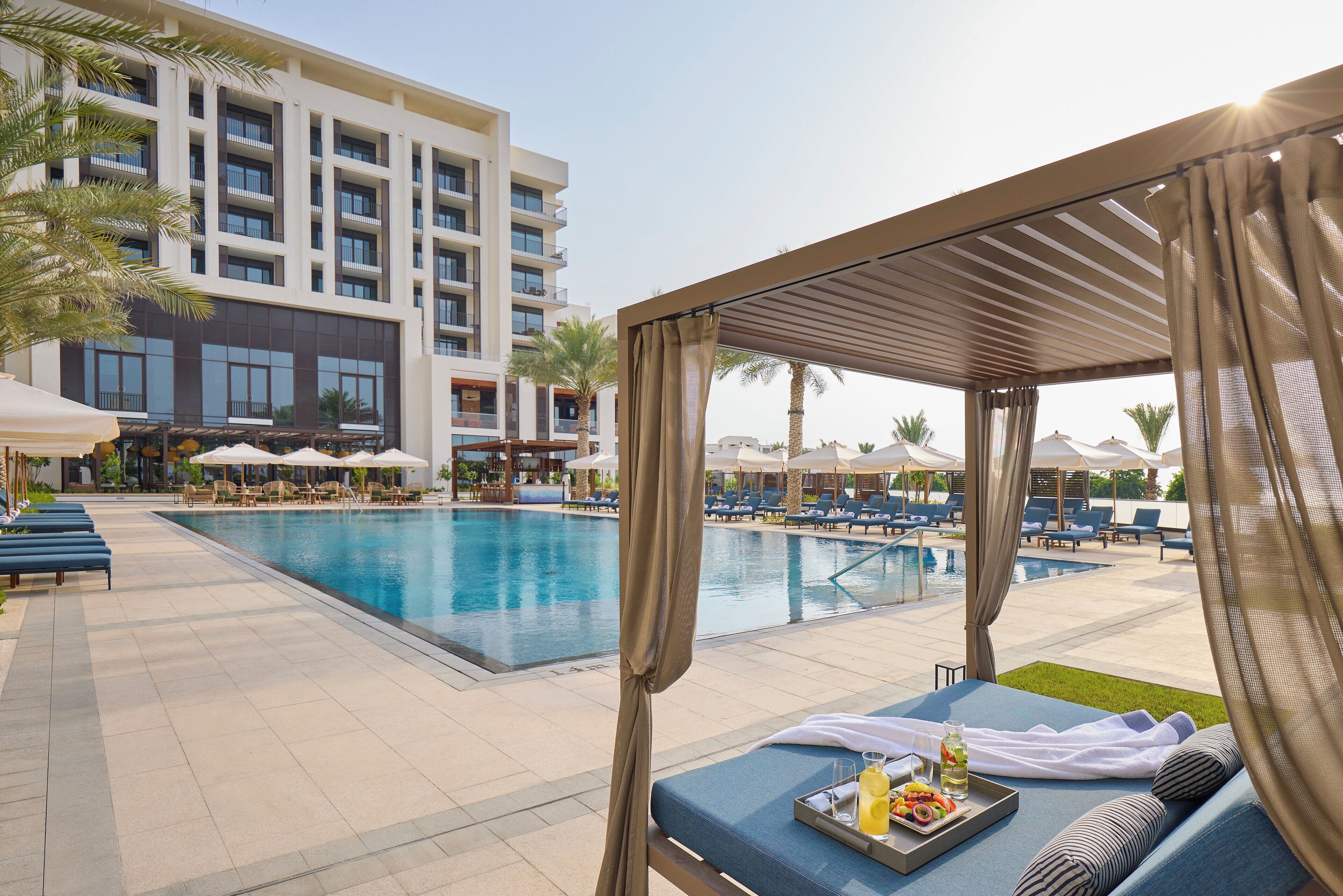 A poolside area with lounge chairs, a cabana, and a buffet tray with drinks and snacks.