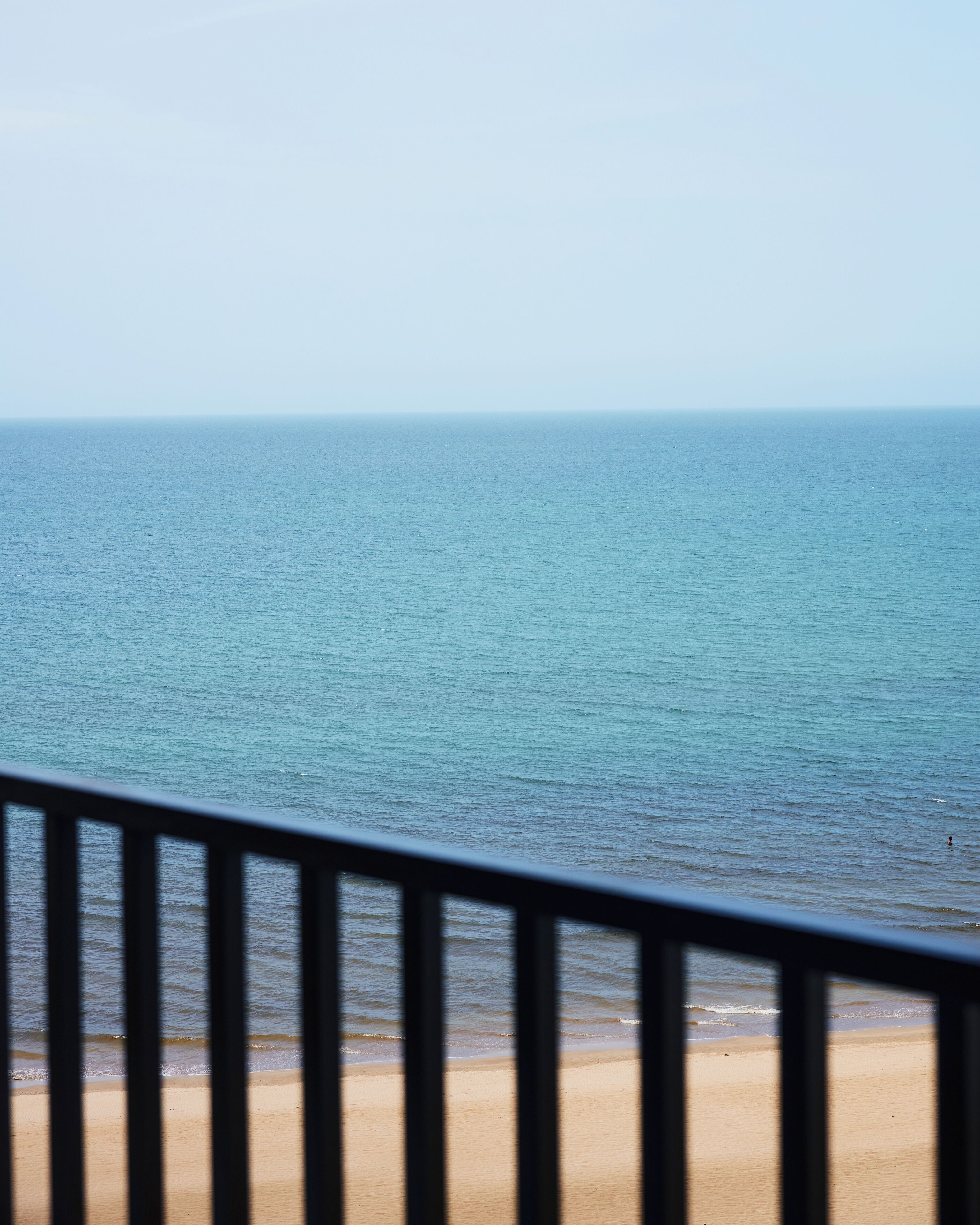 A beach view with a railing in the foreground.