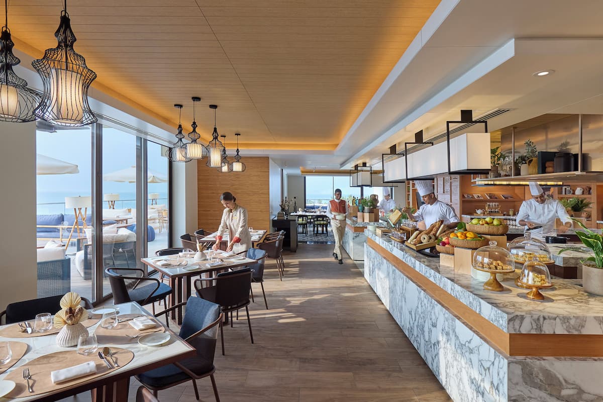 A modern restaurant with a marble counter, dining tables, and chairs.