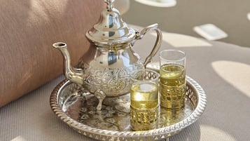 A tray with a teapot and two glasses of tea, placed on a table with a cushion and a magazine.