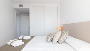 Una habitación de hotel con una cama bien hecha, una lámpara de noche y un juego de toallas en el suelo.