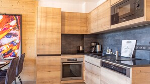 Une cuisine moderne avec des meubles en bois, un four à micro-ondes encastré, une machine à café et un lave-vaisselle.
