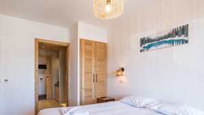 Une chambre à coucher avec un grand lit, une armoire en bois et un tableau représentant un paysage enneigé.