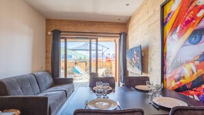 Un coin repas avec une table en bois dressée pour quatre personnes, un canapé gris et un grand tableau accroché au mur.