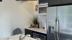 Una cocina moderna con un refrigerador de acero inoxidable, horno empotrado y un lavamanos.