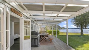 A covered outdoor area with a grill and picnic table, a door labeled "The Middle," and a view of a lake.