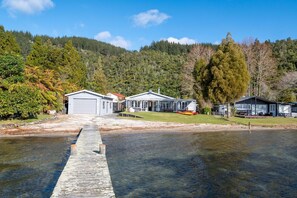 A waterfront property with a dock leading to a house, surrounded by forested hills.