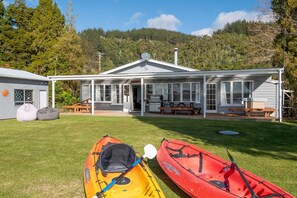 A house with a covered porch, a dining area, and kayaks.