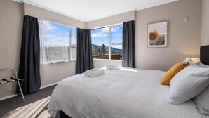 Ein Hotelzimmer mit einem großen Bett, Ausblick ins Freie, einem Sessel und einem Gemälde an der Wand.