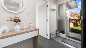 Ein modernes Badezimmer mit einem Holzwaschtisch, einem runden Spiegel und einer Duschkabine aus Glas.