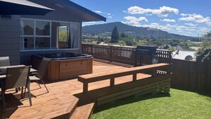 Eine Terrasse mit Gartenmöbeln, einem Whirlpool und Blick auf ein Gebirge.