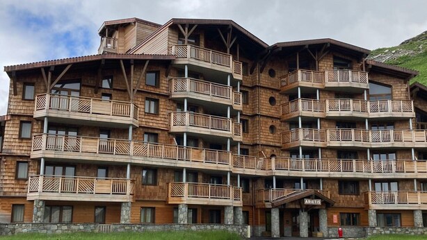 Un hotel de diverses plantes amb balcons de fusta i detalls de pedra.
