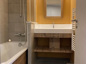 Une salle de bain avec une baignoire, une douche, un lavabo et un miroir.