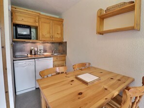 A compact kitchen with wooden cabinets, a microwave, a coffee maker, and a dishwasher. - Charming 2-room apartment near the slopes in Méribel (Méribel)