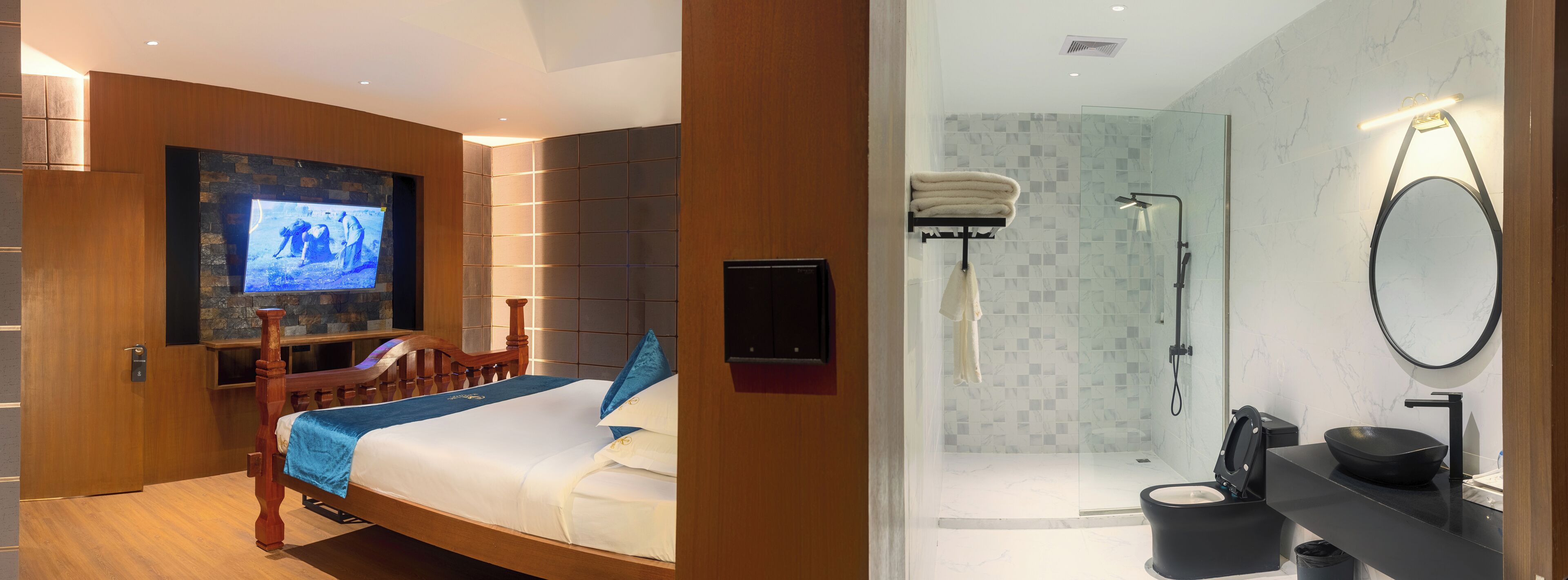 A hotel room with a wooden bed, a television, a shower, and a bathroom with a black sink and mirror.
