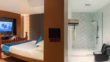 A hotel room with a wooden bed, a television, a shower, and a bathroom with a black sink and mirror.