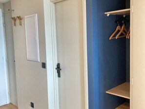 A room with a white door, a blue wall, and wooden hangers on a rack.