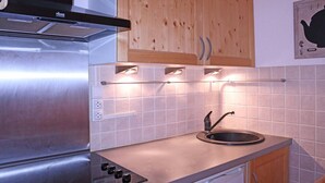 Une cuisine moderne dotée d’appareils électroménagers en acier inoxydable, de meubles en bois et d’un dosseret carrelé.