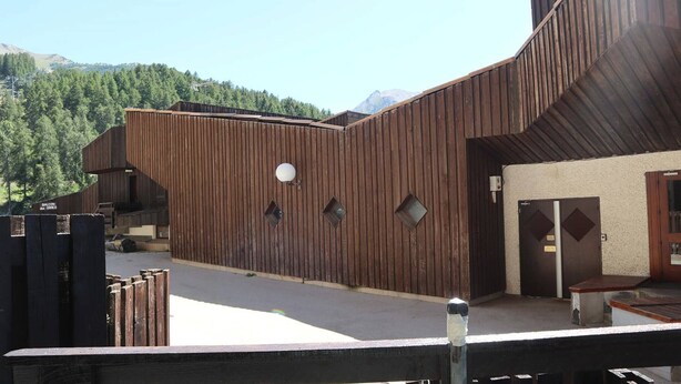 Un bâtiment à l’extérieur en bois, doté d’un balcon et d’une porte sur laquelle est apposée une enseigne.