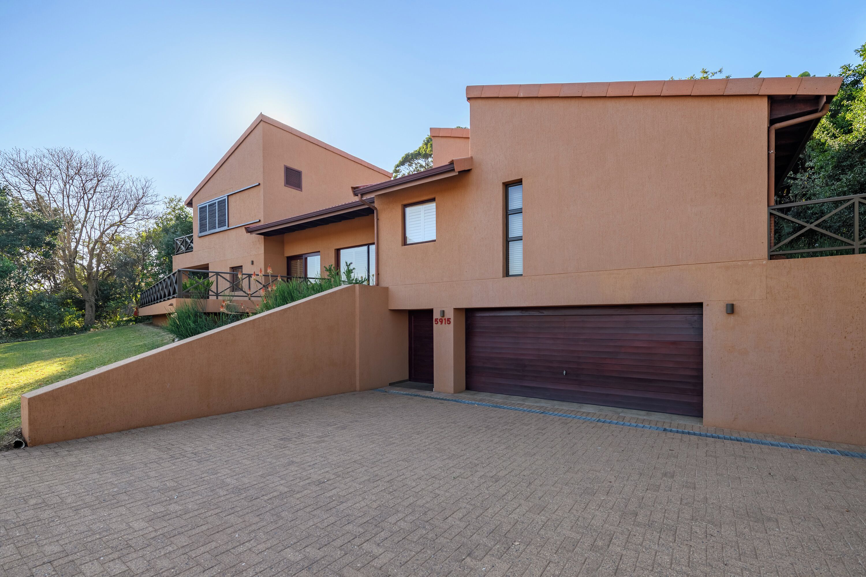 A modern two-story house with a brick driveway, a garage, and a sloped roof.