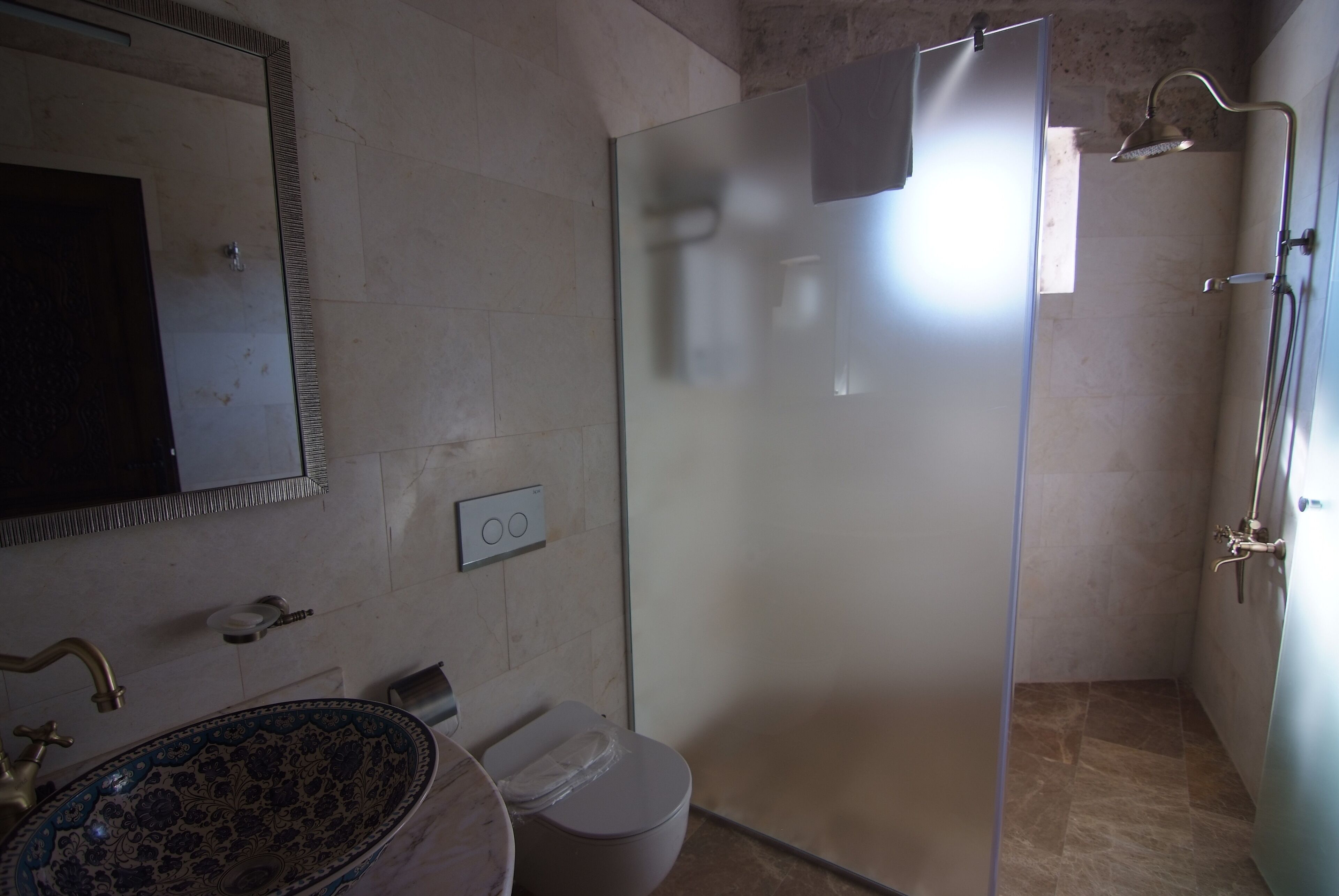 A bathroom with a glass-enclosed shower, a toilet, and a sink with a decorative basin.