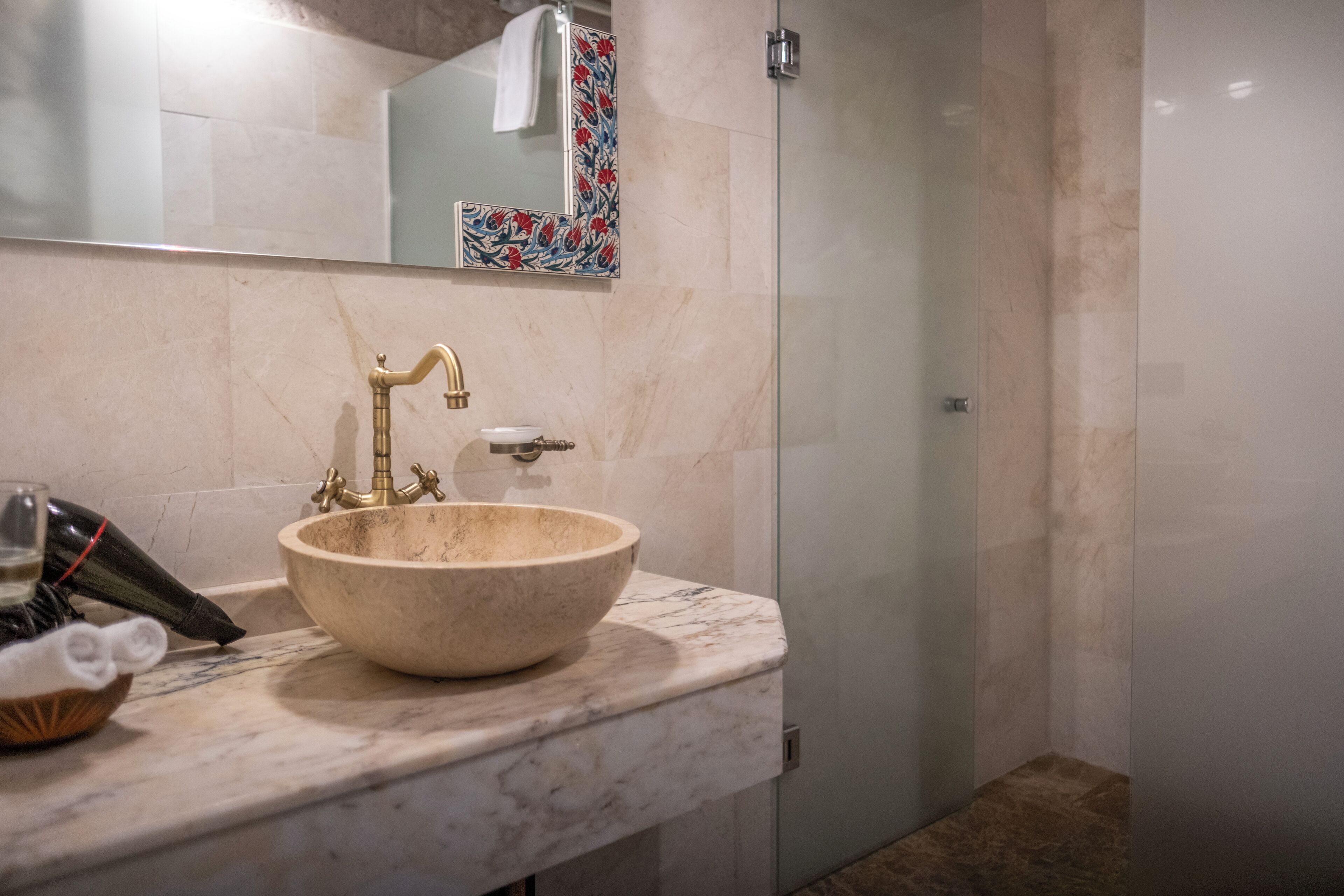 A bathroom with a marble sink, a glass shower enclosure, and a decorative tile backsplash.