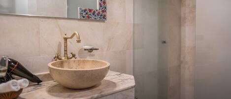 A bathroom with a marble sink, a glass shower enclosure, and a decorative tile backsplash.