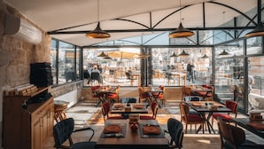 A restaurant with a modern interior, featuring exposed brick walls, large windows, and a variety of seating arrangements. - Peruna Cave (Nevsehir)